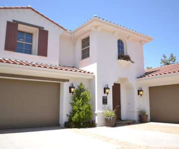 A modern two-story house with a white concrete exterior and a closed garage door.