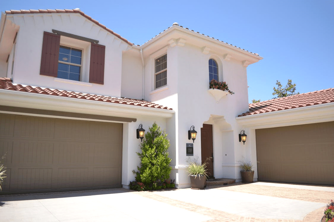 A modern two-story house with a white concrete exterior and a closed garage door.