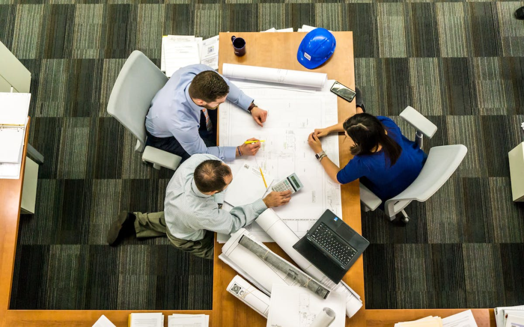 Three individuals having a meeting while reviewing documents