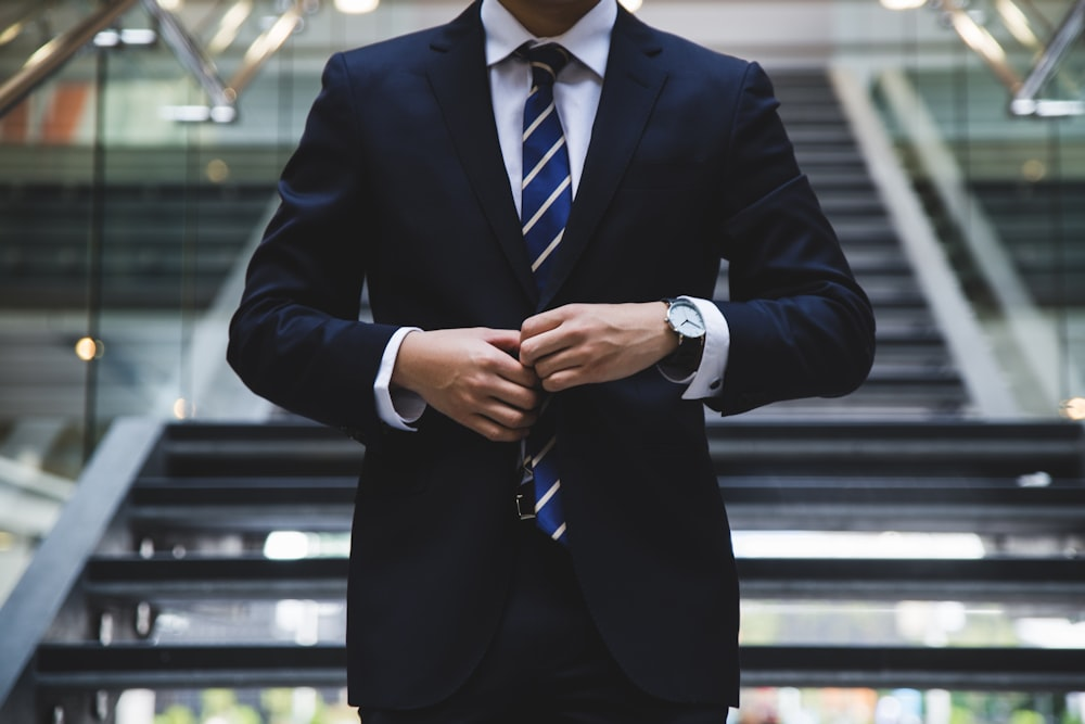 A man in a formal suit buttoning his coat