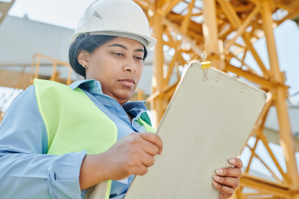 A woman wearing a safety helmet holding a whiteboard 