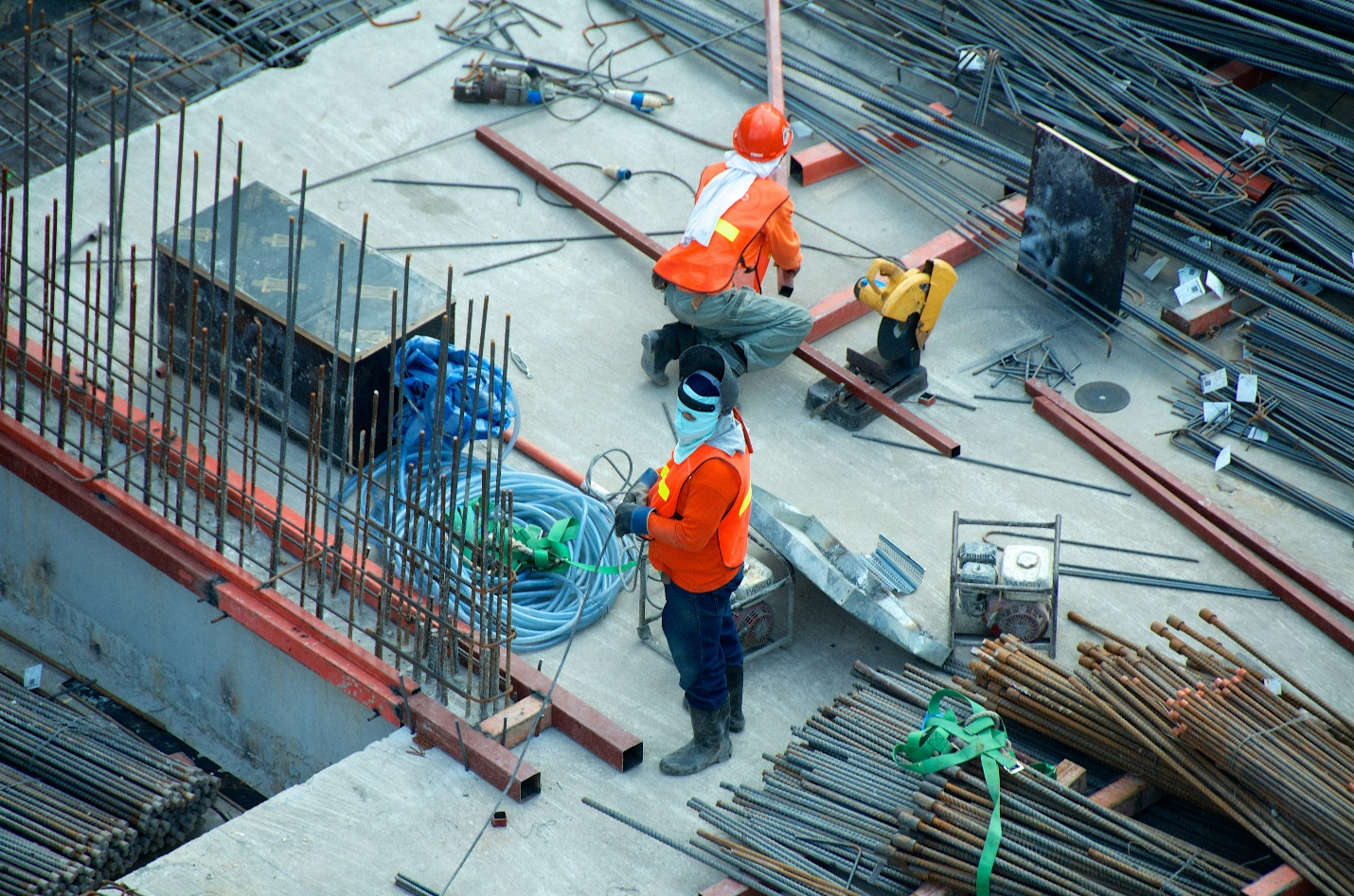 Two men in orange safety vests at a construction site