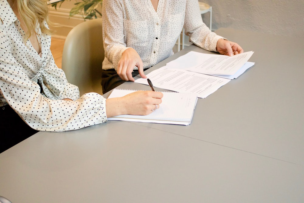 An image of two women signing some papers 